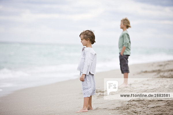 Zwei Jungen  die am Strand stehen.