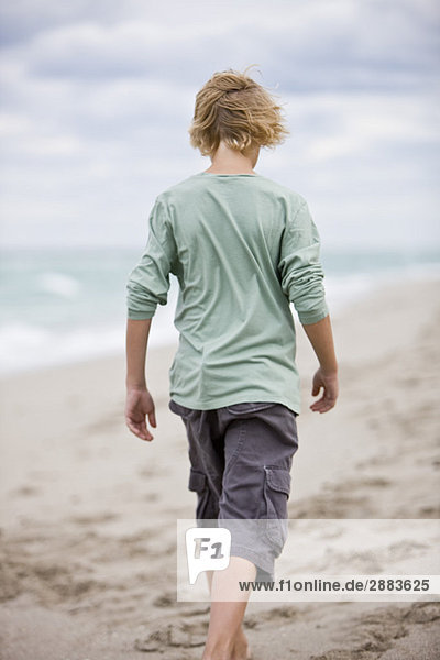 Rear view of a boy walking on the beach