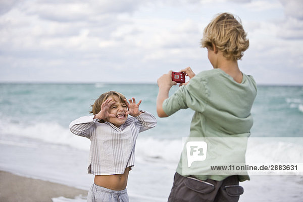Junge fotografiert seinen Bruder mit einer Digitalkamera