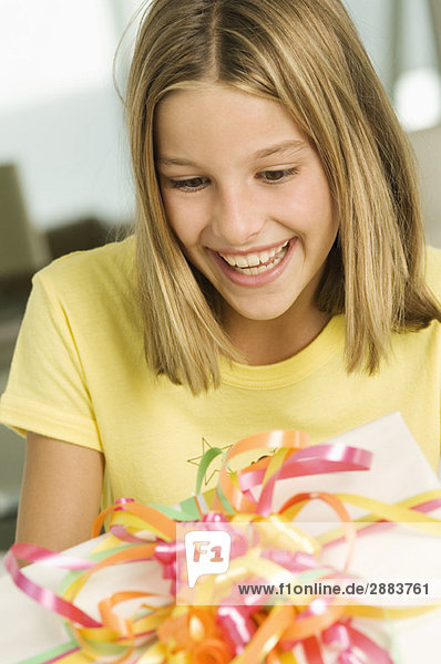 Mädchen schaut auf ein Geburtstagsgeschenk und lächelt