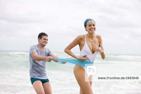 Man pulling sarong of a woman on the beach