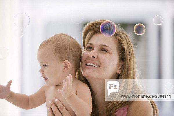 Woman and her daughter trying to catch soap bubbles