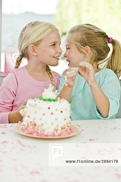 Zwei Mädchen lächeln vor einer Geburtstagstorte