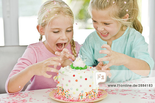 Zwei Mädchen beim Anblick eines Geburtstagskuchens