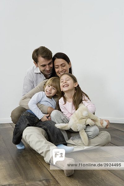 Eine vierköpfige Familie  die lacht und sich umarmt.