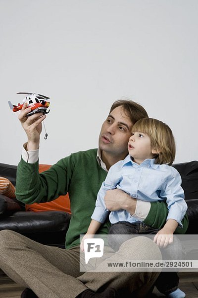 A father and son playing with a toy helicopter