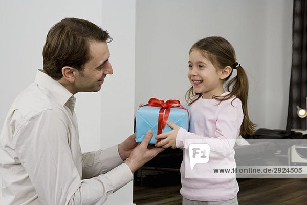 Ein Vater  der seiner Tochter ein Geschenk macht.