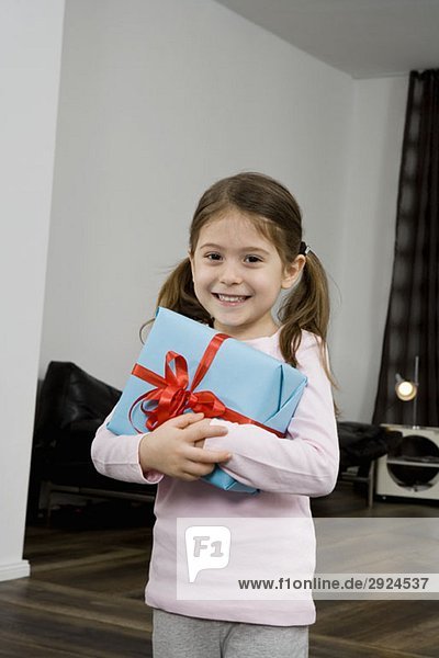 Ein junges Mädchen mit einem verpackten Geschenk.