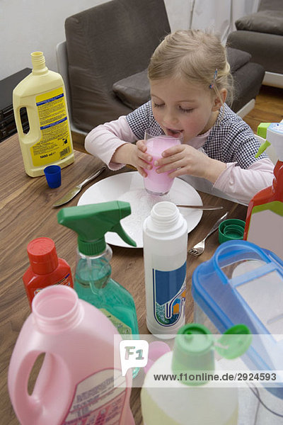 A young girl drinking cleaning fluid surrounded by medicines