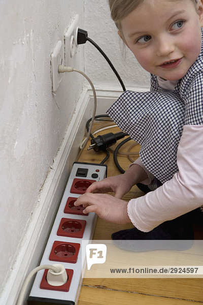 A young girl touching an electric outlet