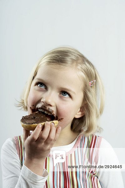 A young girl eating bread and chocolate spread