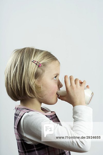 A young girl drinking a glass of milk
