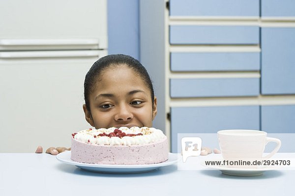 Eine junge Frau  die auf einen Kuchen schaut.