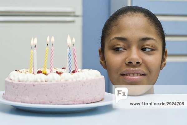 Eine junge Frau  die auf einen Geburtstagskuchen schaut.
