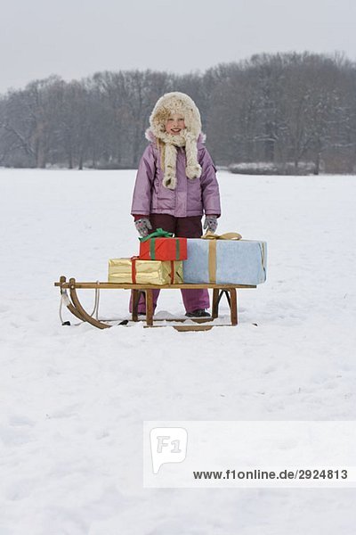 A young girl with a sled with presents