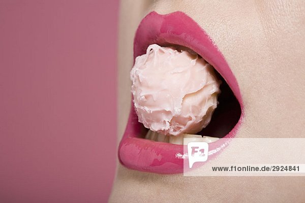 A woman's mouth with a pink truffle