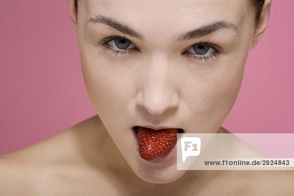 Eine Frau mit einer Erdbeere im Mund.