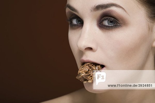 Eine Frau mit einer Mandelschokolade im Mund.
