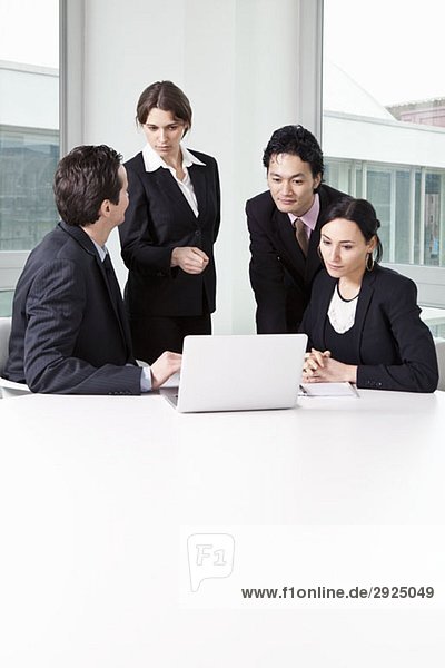Four business people in a meeting using a laptop
