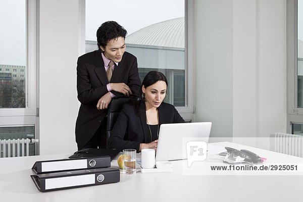 Ein Geschäftsmann und eine Geschäftsfrau  die auf einen Laptop schauen.