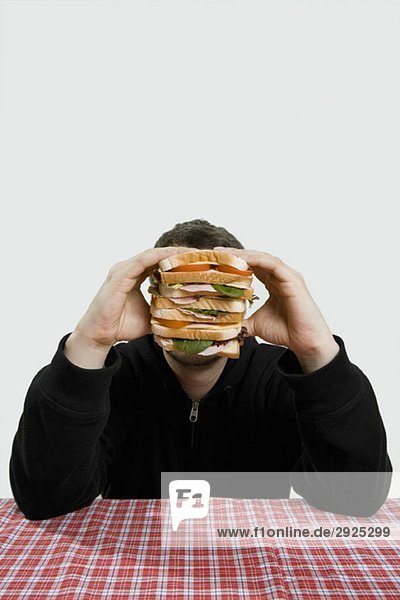 Ein Mann hält ein großes Sandwich.