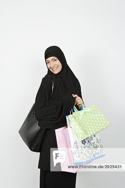 Eine Frau  die einen Hijab trägt und Einkaufstaschen hält.