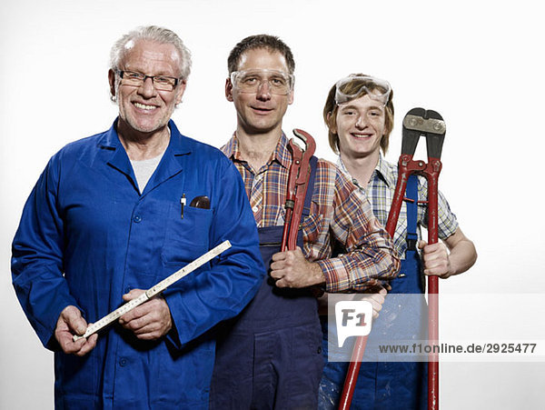 Three manual workers holding tools