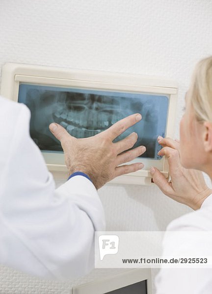 Detail eines Zahnarztes und einer Zahnarzthelferin beim Betrachten einer Röntgenaufnahme