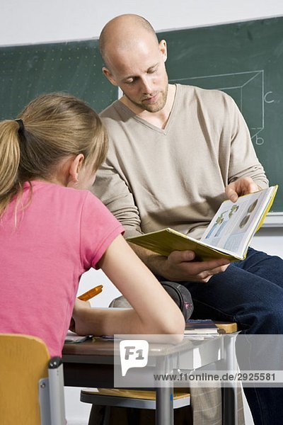 Ein Lehrer betrachtet ein Buch mit einem Schüler