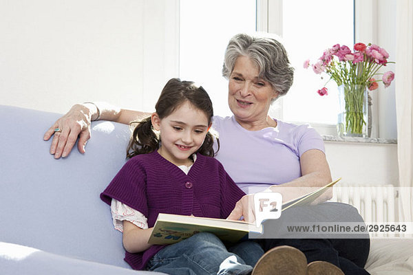 Eine Großmutter liest mit ihrer Enkelin ein Buch.
