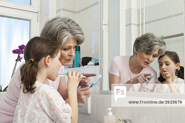 Eine Großmutter  die ihrer Enkelin beibringt  wie man Zähne putzt.