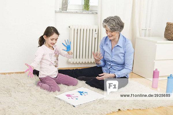 A grandmother and her granddaughter finger painting