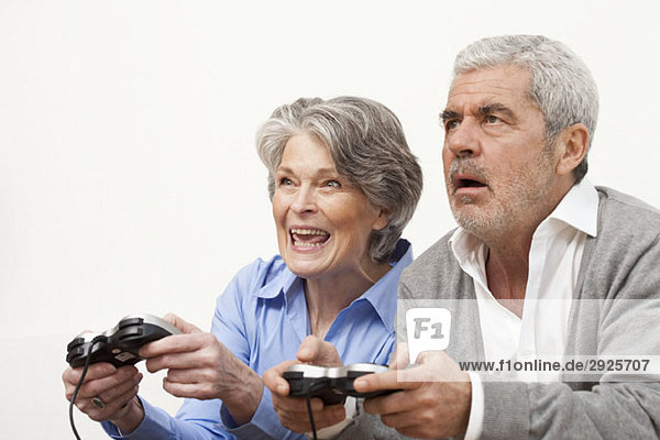 Ein älterer Mann und eine ältere Frau spielen ein Videospiel.