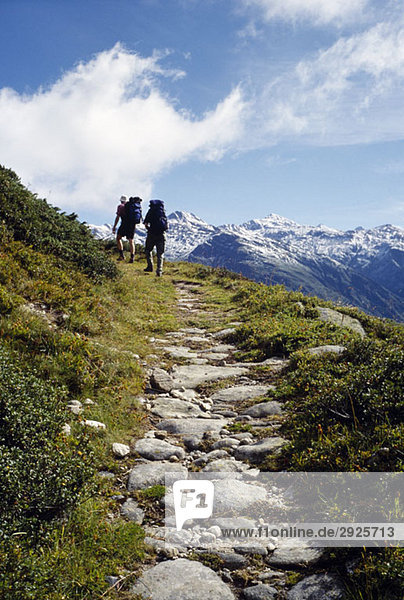 Two people hiking up a mountain path  Valais  Switzerland