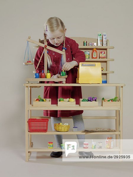 A girl playing in a children's wooden grocery store