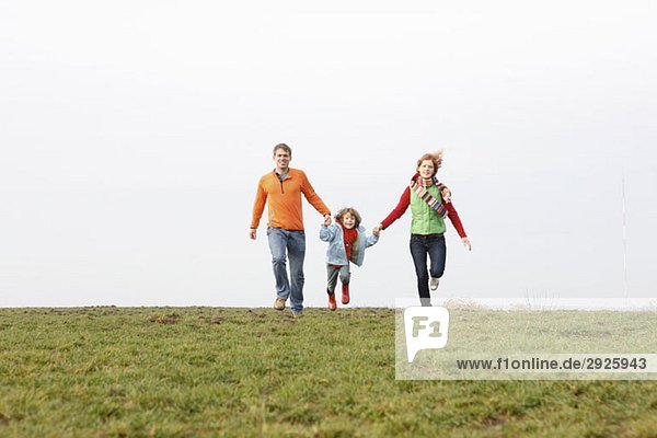 A young family running together in a park