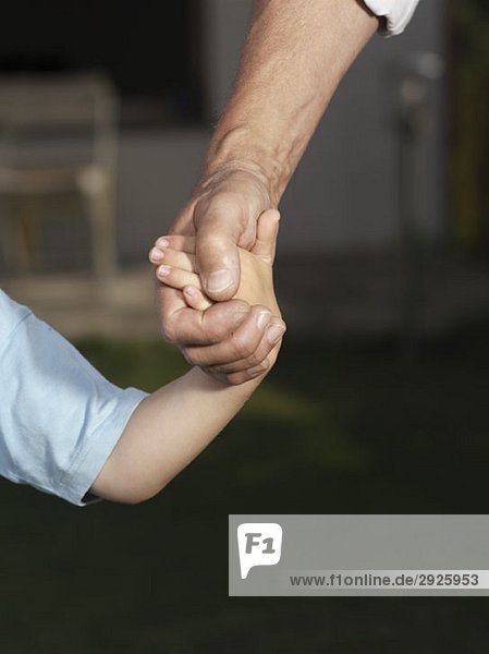 Detail of a child and a man holding hands