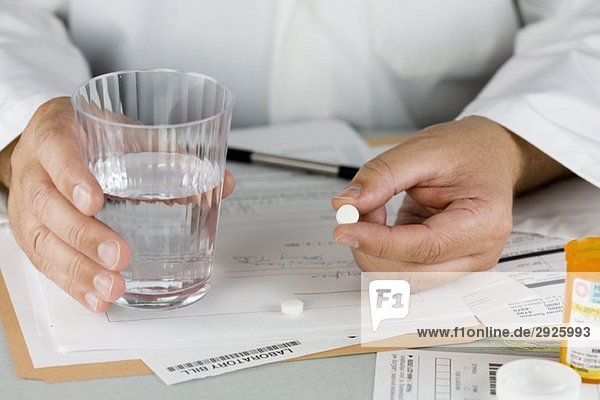 A doctor offering a pill and glass of water