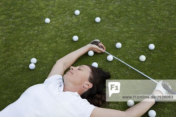 Ein erschöpfter Golfer  der auf einem Golfplatz liegt.