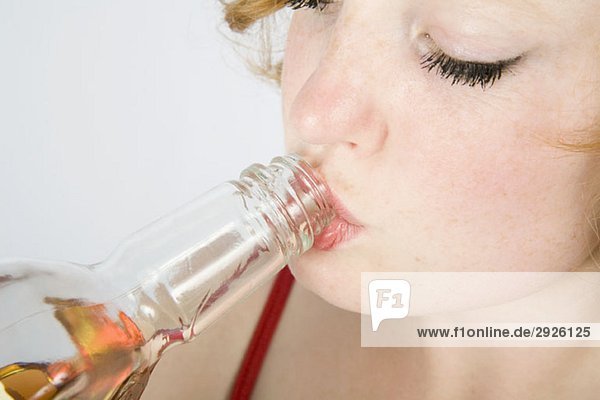 Eine junge Frau  die aus einer Glasflasche trinkt.