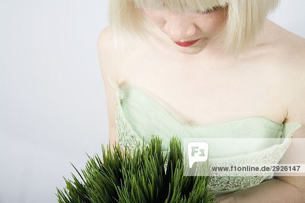 Eine junge Frau  die eine Weizengraspflanze hält.