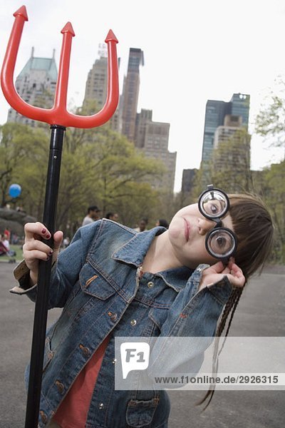 Ein junges Mädchen mit einer lustigen Brille und einer Teufelsgabel.