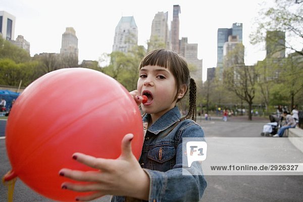 Ein junges Mädchen sprengt einen Ballon im Central Park  New York City.