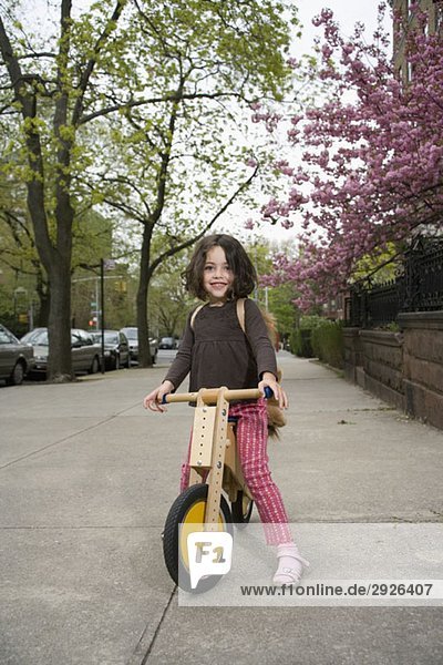 A young girl on a wooden scooter
