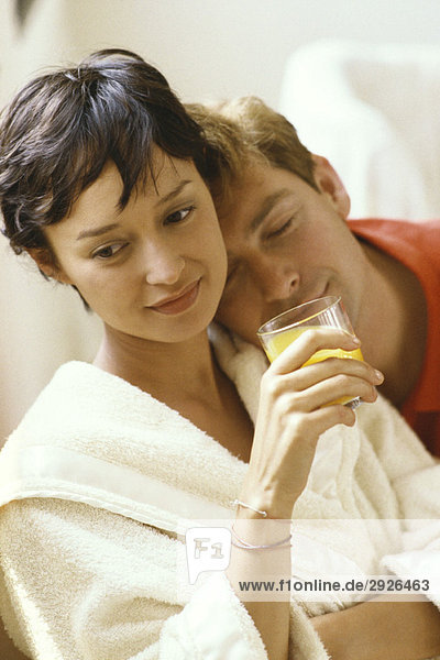 Frau im Bademantel und mit einem Glas Saft  Mann ruht Kopf auf der Schulter