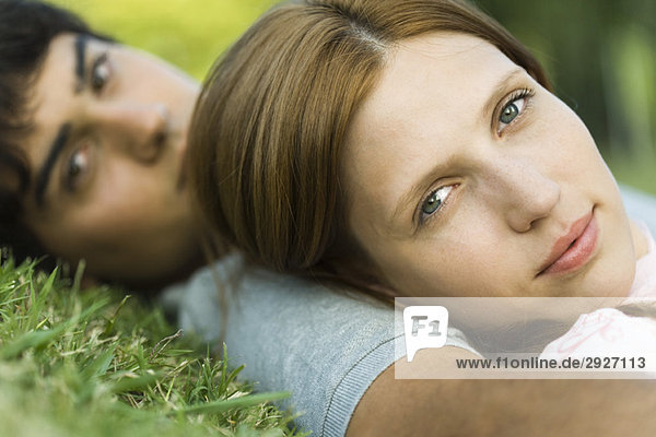 Junges Paar auf Gras liegend  in die Kamera schauend  Nahaufnahme
