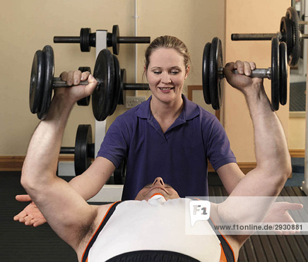 Mann trainiert mit Gewichten im Fitnessstudio