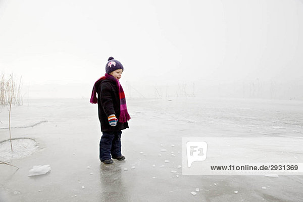 Junge auf gefrorenem See im Nebel