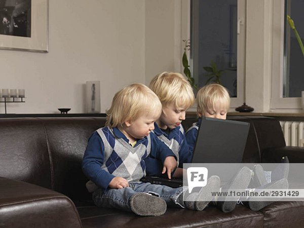 Drei Kleinkinder arbeiten am Laptop