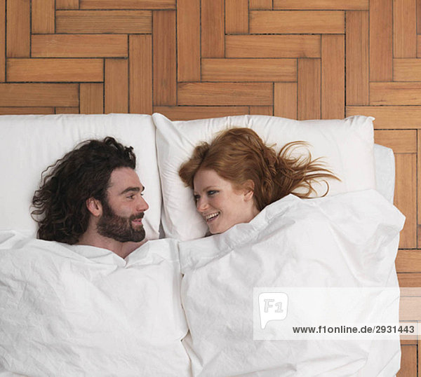 Couple lying in bed  smiling
